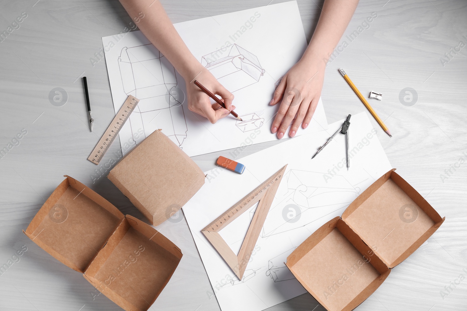 Photo of Woman creating packaging design at light wooden table, top view