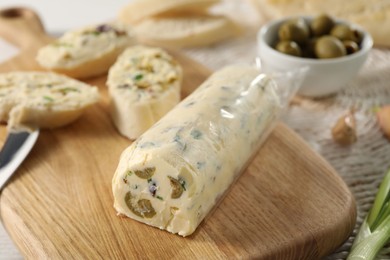 Photo of Tasty butter with olives, green onion and bread on table, closeup