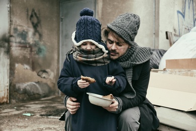 Poor father and child with bread at dump