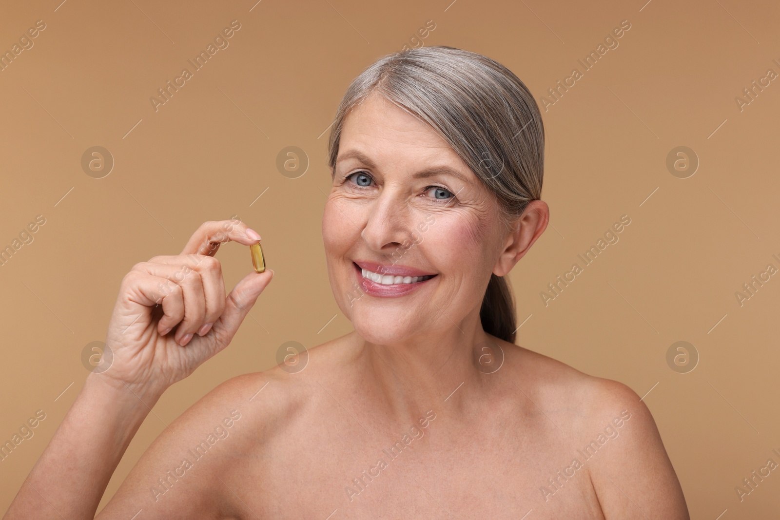 Photo of Beautiful woman with vitamin capsule on beige background