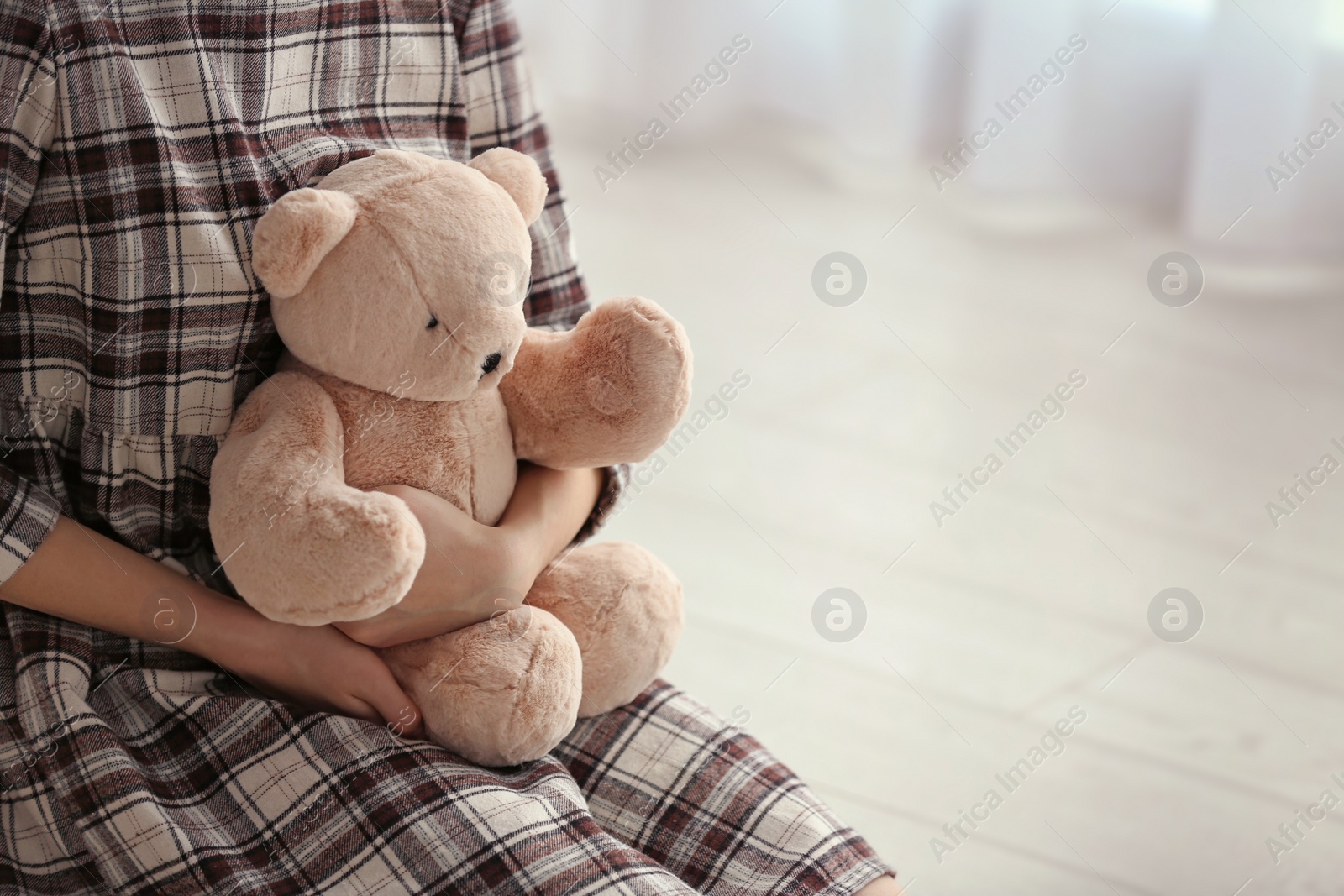 Photo of Upset girl with toy indoors, closeup. Space for text