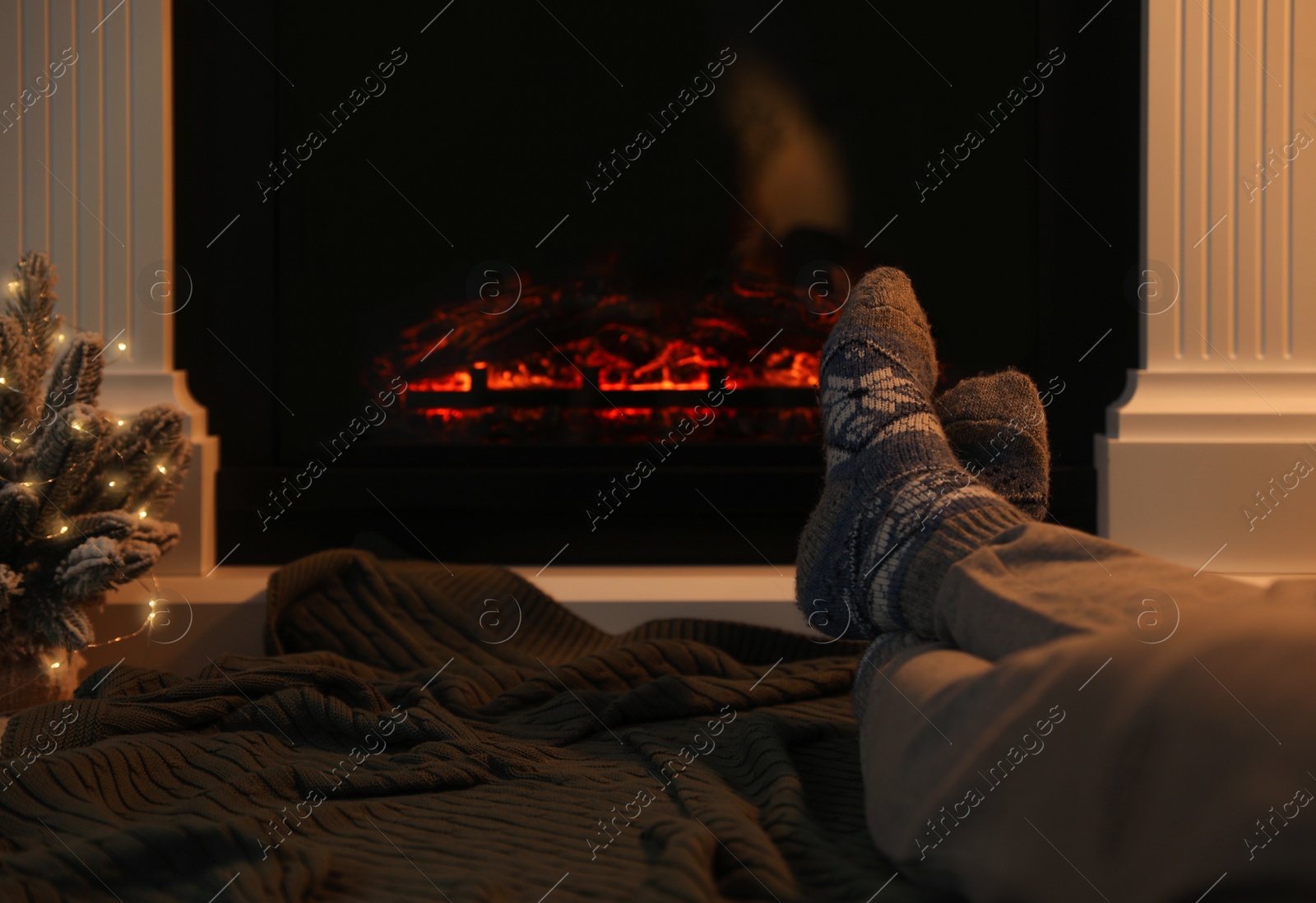 Photo of Man in warm socks resting near fireplace at home, closeup. Space for text
