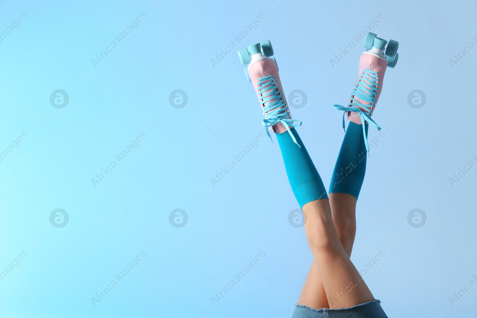 Photo of Woman with vintage roller skates on color background, closeup. Space for text