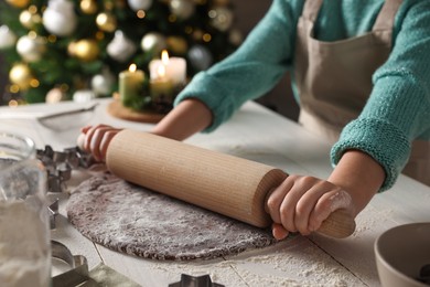 Little child rolling dough for Christmas cookies at white wooden table indoors, closeup