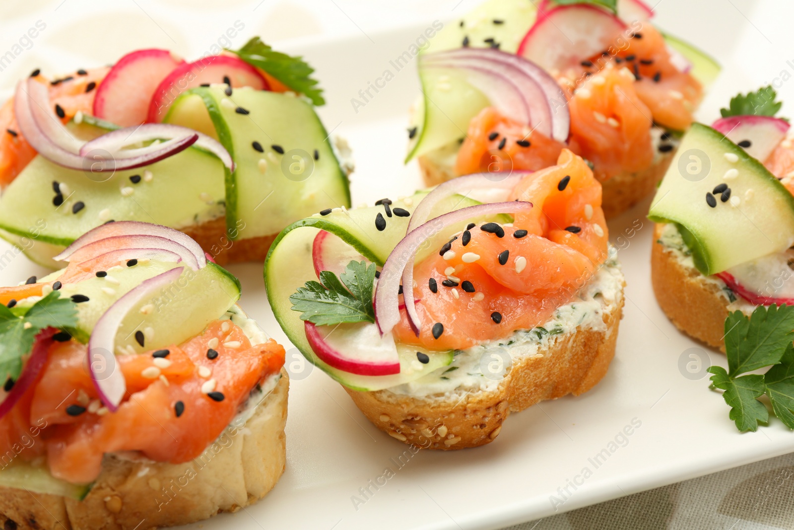 Photo of Tasty canapes with salmon served on white wooden table, closeup