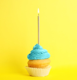 Birthday cupcake with candle on yellow background