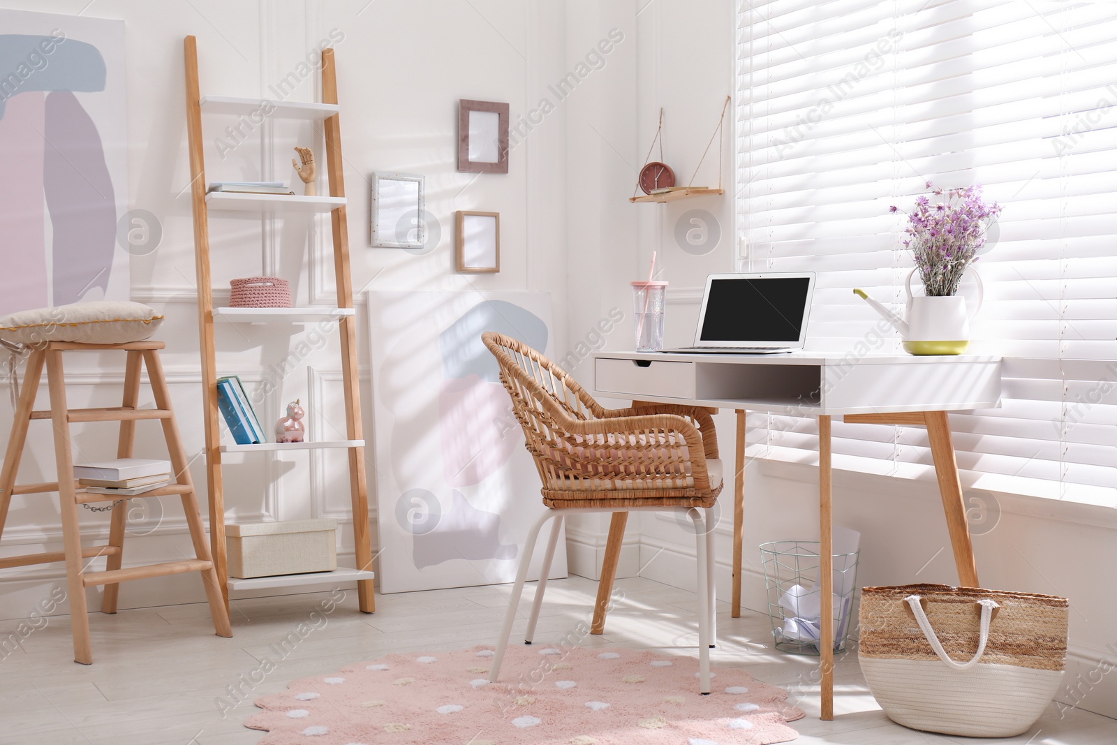 Photo of Comfortable workplace with modern laptop and flowers in room. Interior design