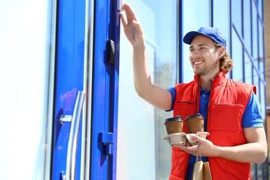 Photo of Male courier with order ringing in doorbell at entrance. Food delivery service