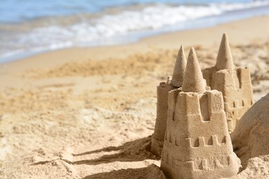 Photo of Beach with sand castle near sea on sunny day. Space for text