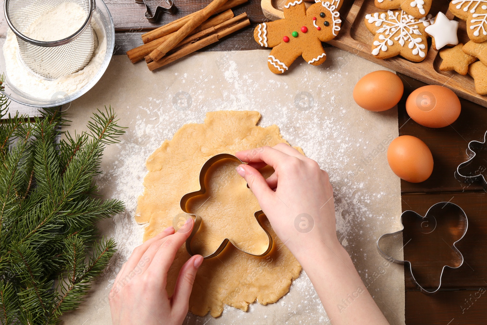 Photo of Woman making Christmas cookies with cutters at wooden table, top view