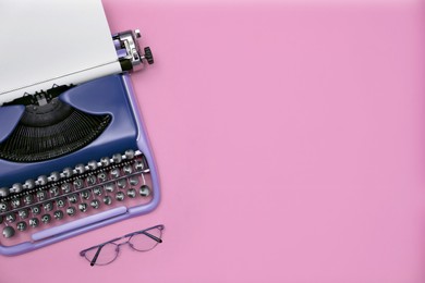 Copywriter. Vintage typewriter and eyeglasses on pink background, top view. Space for text