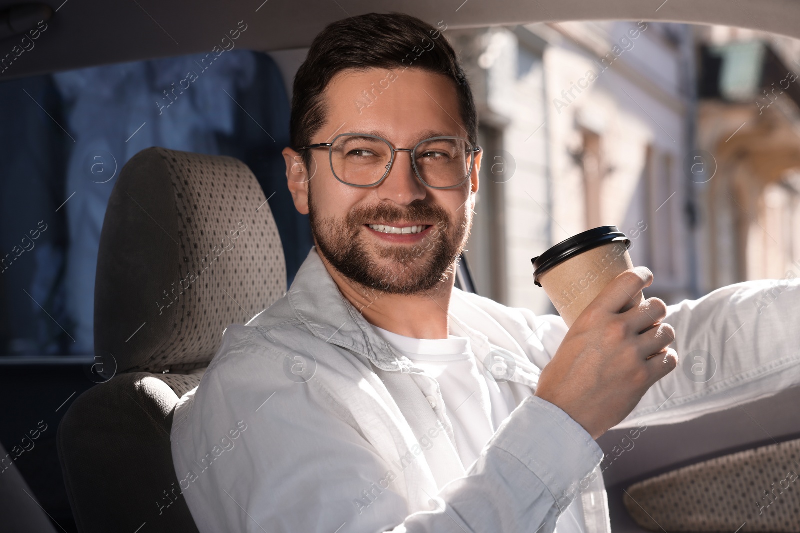 Photo of Coffee to go. Happy man with paper cup of drink in car