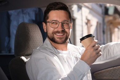 Photo of Coffee to go. Happy man with paper cup of drink in car