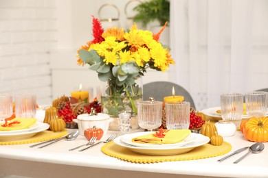 Photo of Autumn table setting with floral decor and pumpkins indoors