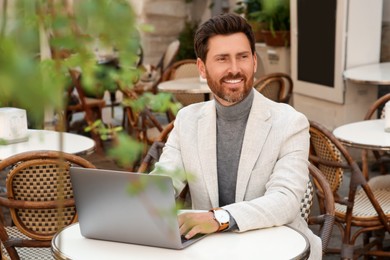 Photo of Man with laptop at table in outdoor cafe
