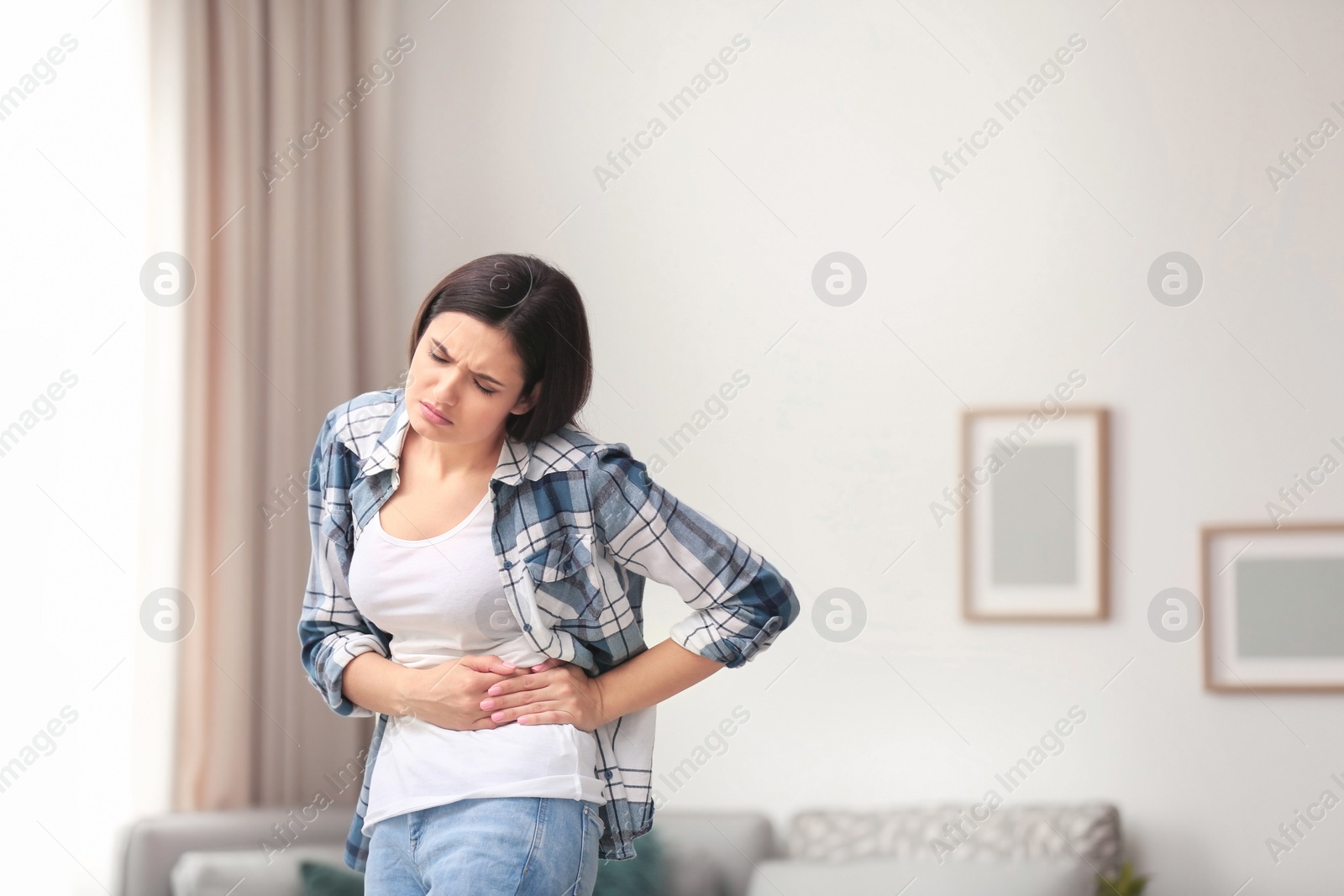 Photo of Young woman suffering from pain in her side at home