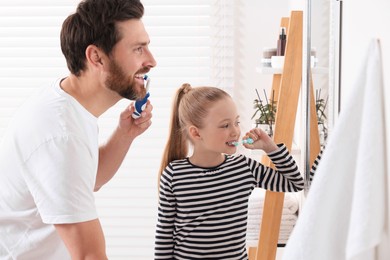 Father and his daughter brushing teeth together in bathroom