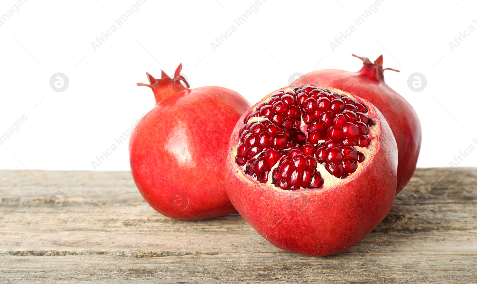 Photo of Fresh pomegranates on wooden table against white background