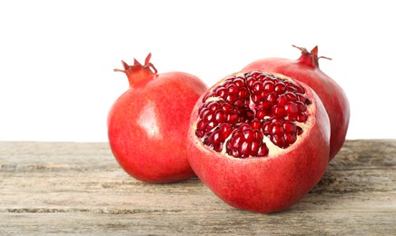 Fresh pomegranates on wooden table against white background