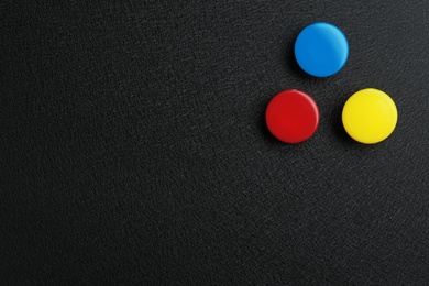Bright magnets on black background, top view with space for text