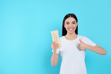 Happy young woman with delicious shawarma on light blue background. Space for text