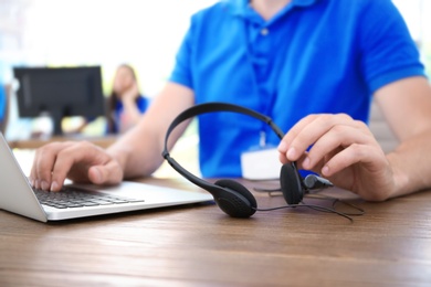 Photo of Male technical support operator with headset at workplace, closeup