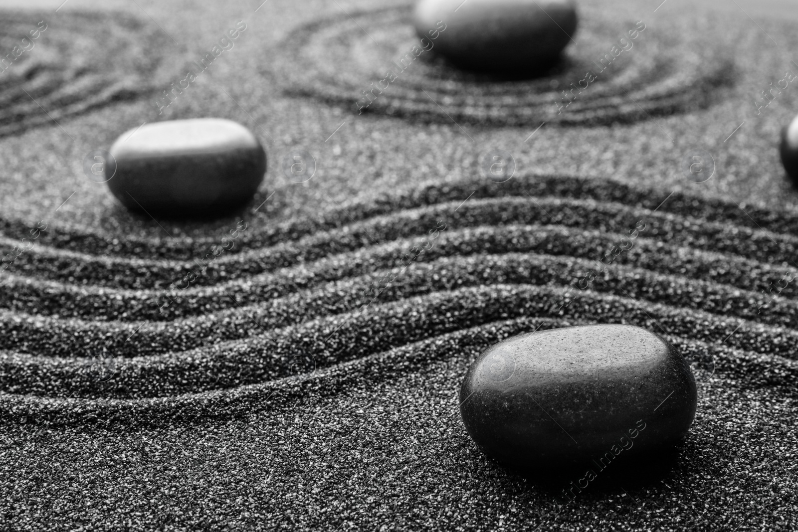 Photo of Black sand with stones and beautiful pattern. Zen concept