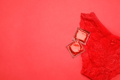 Photo of Lace panties and condoms on red background, top view with space for text. Safe sex