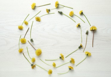 Photo of Frame of beautiful yellow dandelions on white wooden table, flat lay. Space for text