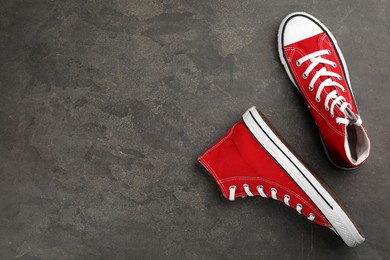 Photo of Pair of red sneakers on grey stone table, flat lay. Space for text