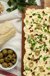 Photo of Fresh butter board with olives, sun-dried tomatoes and bread on table, flat lay