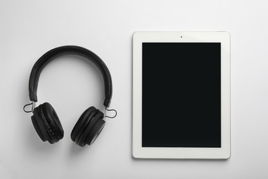 Stylish headphones and modern tablet on white background, top view. Space for text