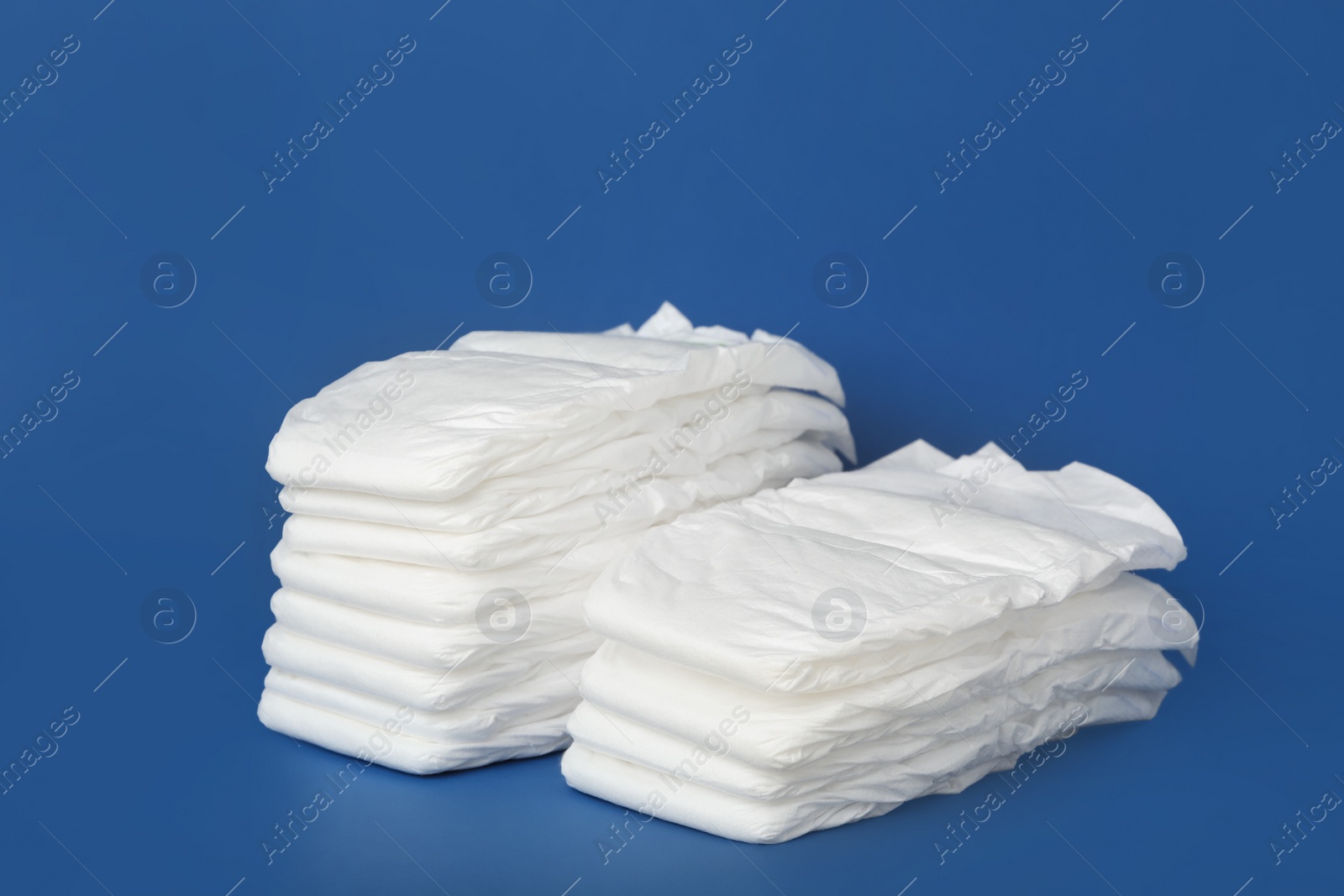 Photo of Stack of baby diapers on blue background