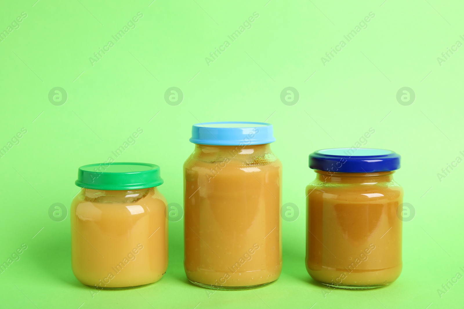 Photo of Jars with baby food on green background