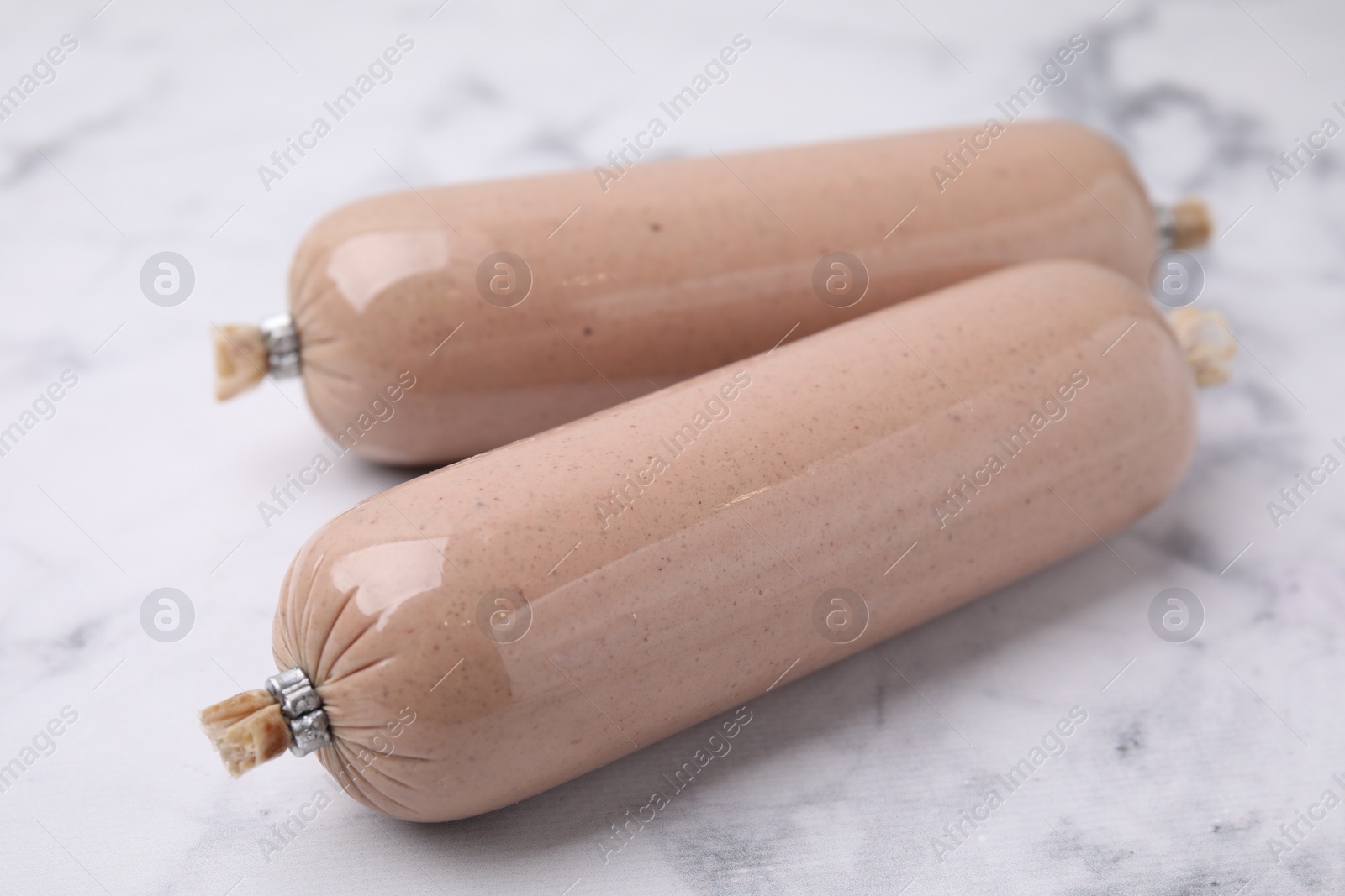 Photo of Delicious liver sausages on white marble table