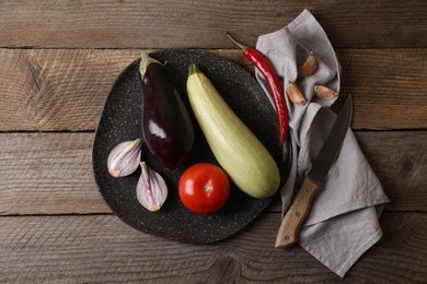 Photo of Cooking ratatouille. Vegetables and knife on wooden table, flat lay