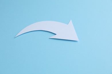 Photo of White curved paper arrow on light blue background, space for text