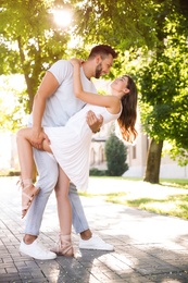 Lovely young couple dancing together in park on sunny day