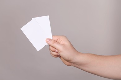 Photo of Woman holding paper cards on grey background, closeup. Mockup for design