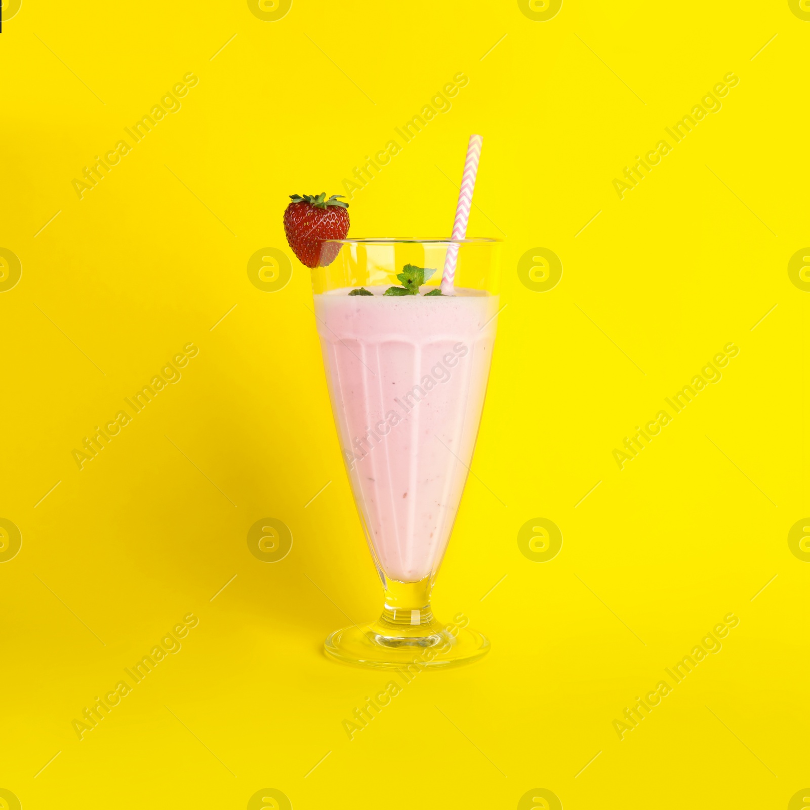 Photo of Tasty fresh milk shake with strawberry on yellow background