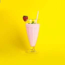 Photo of Tasty fresh milk shake with strawberry on yellow background