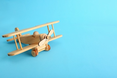 Photo of Wooden toy plane on blue background. Space for text