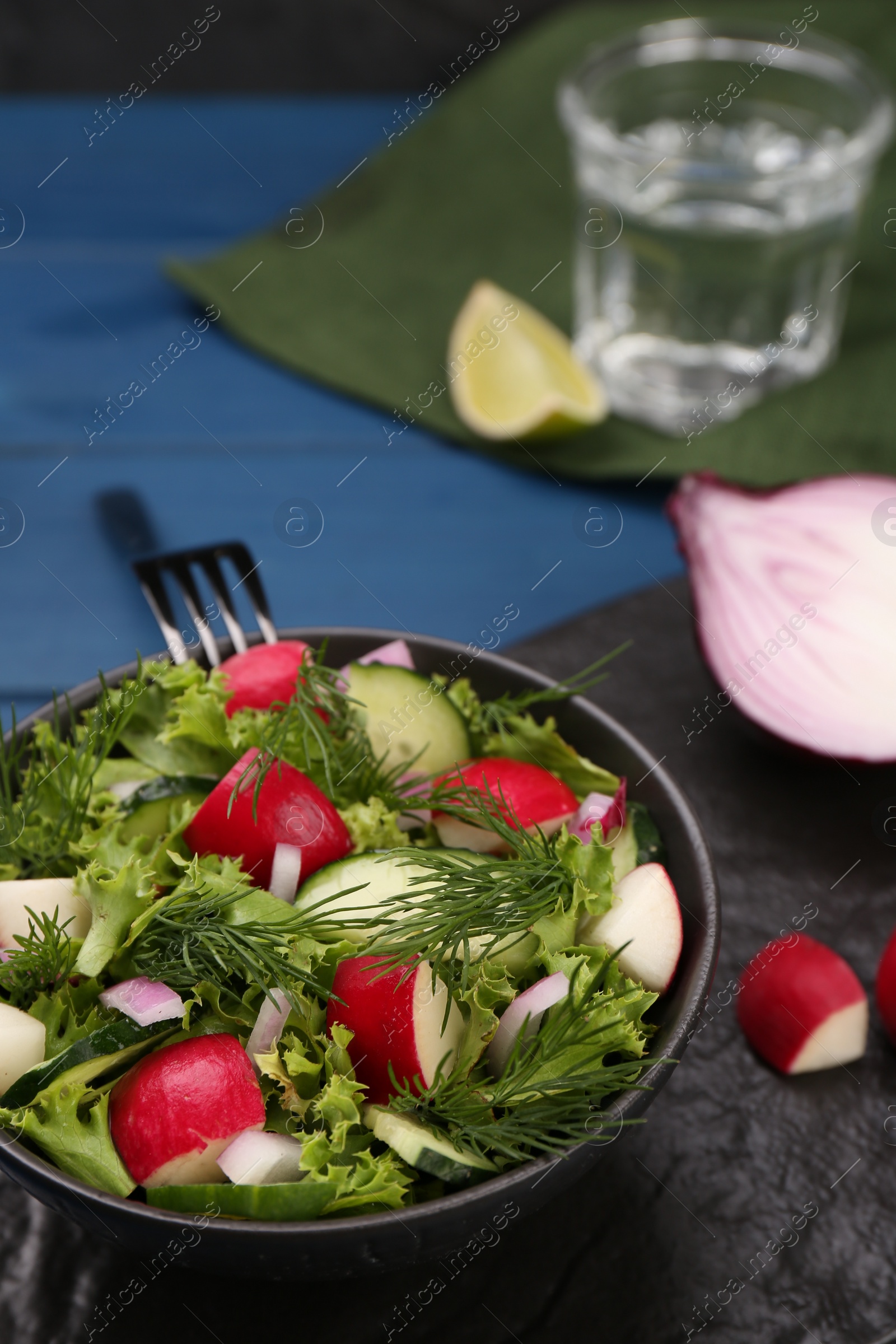 Photo of Tasty salad with radish in bowl on blue table