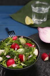 Tasty salad with radish in bowl on blue table