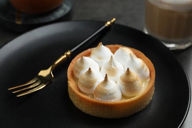 Photo of Tartlet with meringue served on black table, closeup. Delicious dessert