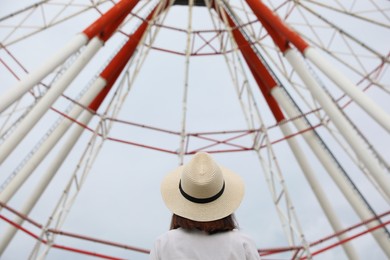 Young woman near Ferris wheel outdoors, back view