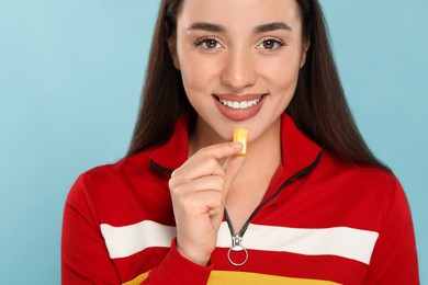 Photo of Happy young woman with bubble gum on light blue background