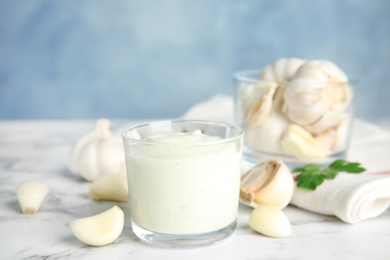 Photo of Composition with glass of garlic sauce on marble table. Space for text