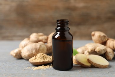 Photo of Ginger essential oil in bottle on light grey table