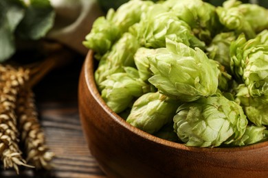 Photo of Fresh hop flowers and wheat ears on wooden table, closeup